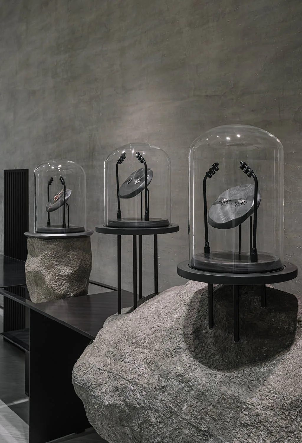Espositori gioielli su rocce naturali nella boutique Zaura, con teche in vetro e struttura in metallo nero, esempio di arredamento gioiellerie di design su misura