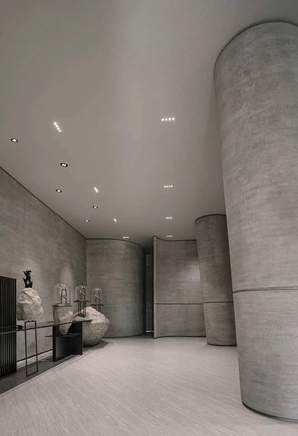 Espositori scultorei su rocce naturali nella boutique Zaura, esempio di arredamento gioiellerie di design con volumi curvi e finiture in cemento