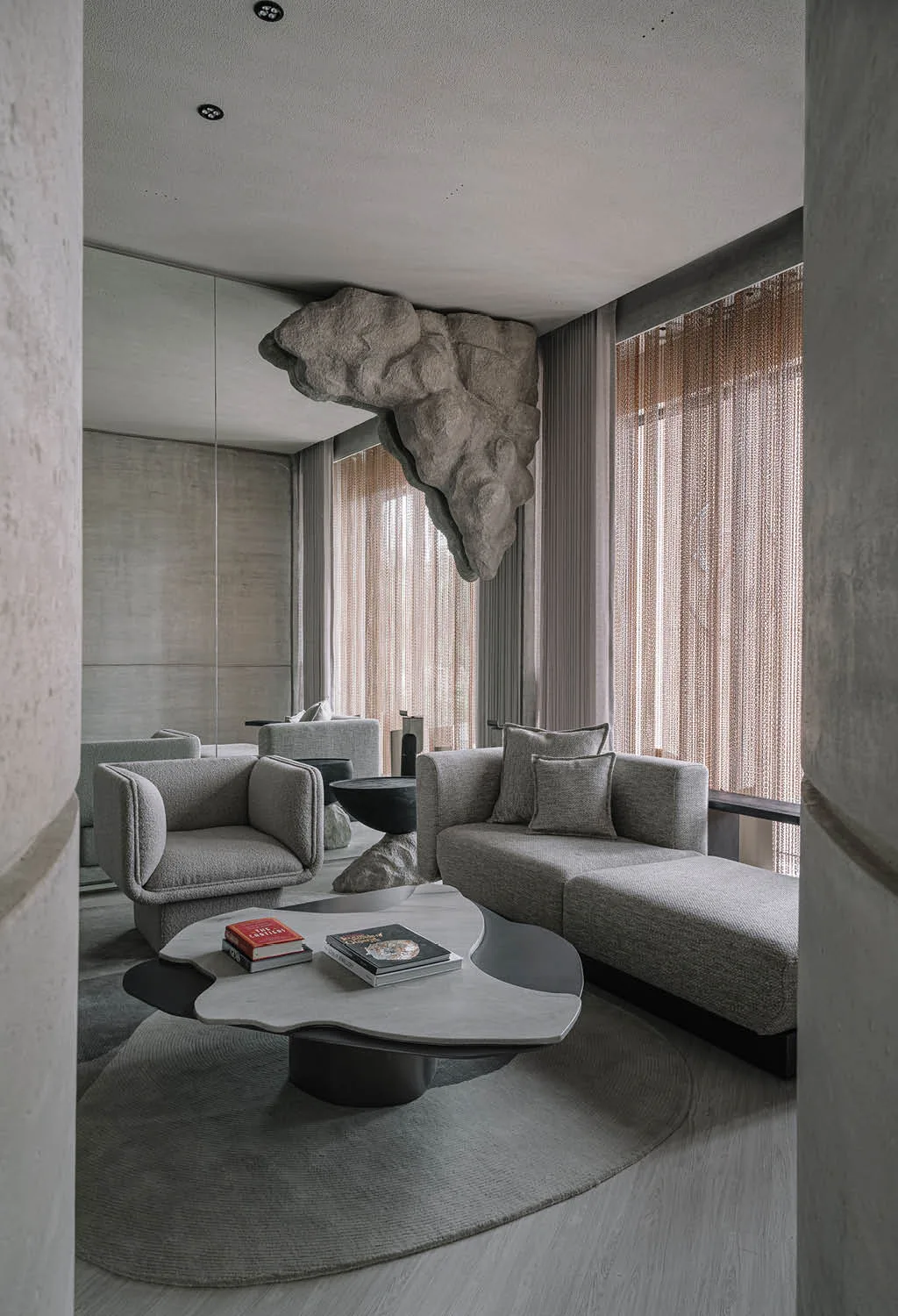 Area relax della boutique Zaura con divani su misura, tavolo scultoreo e installazione rocciosa sospesa, esempio di arredamento gioiellerie di design ispirato alla natura