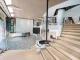 Vista d’ingresso dello showroom Team Value con scala in legno, camino sospeso e pavimento decorativo in bianco e nero
