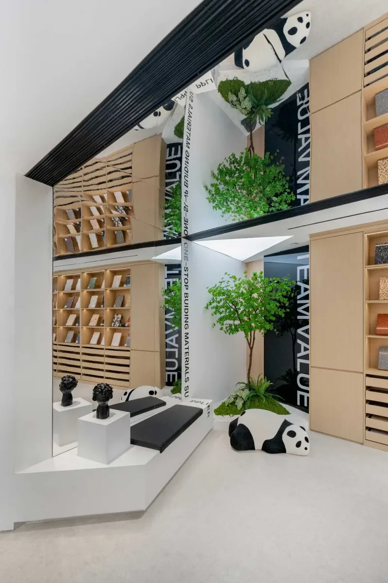 Zona lounge dello showroom Team Value con specchio a soffitto, scaffalature in legno, elementi decorativi a forma di panda e piante verdi