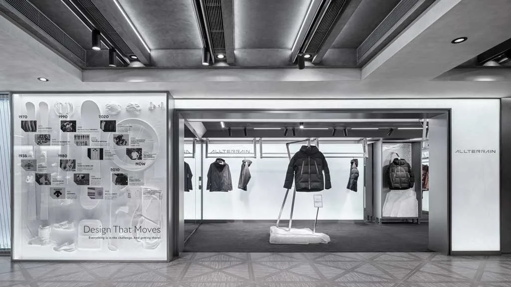 Area Allterrain del flagship store DESCENTE a Harbour City con capi tecnici sospesi e pannello cronologico dedicato all’evoluzione del design sportivo