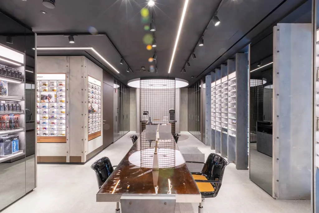 Area di consulenza e personalizzazione all'interno del flagship store Oakley a Milano, con espositori retroilluminati e arredi dallo stile industriale