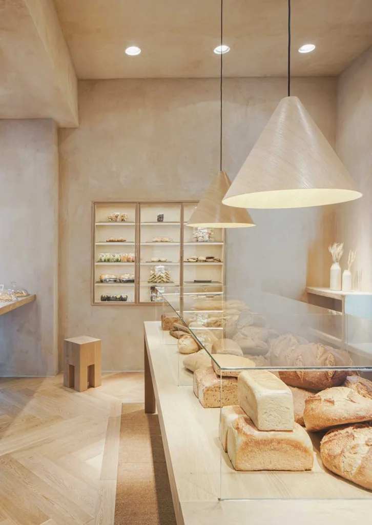 Artisanal bread displayed on a wooden counter at Babette Bakery on General Díaz Porlier in Madrid, an example of convivial-style interior design for bakeries.