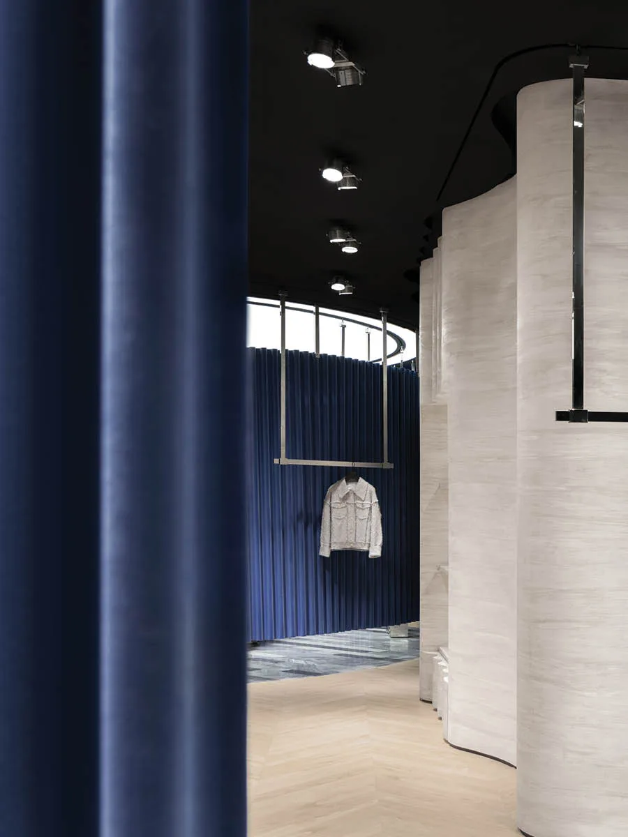 Dettaglio degli interni con pareti curve e tende blu nella boutique MITHRIDATE a Guangzhou