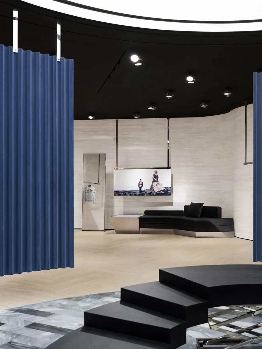 Interior view of the MITHRIDATE boutique in Guangzhou with blue curtains, stepped platform, and integrated seating – an example of experiential retail design by SLT Design