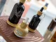 Flaconi cosmetici in vetro scuro con tappo effetto legno esposti a Packaging Première & PCD Milan 2025 su supporto in legno scolpito