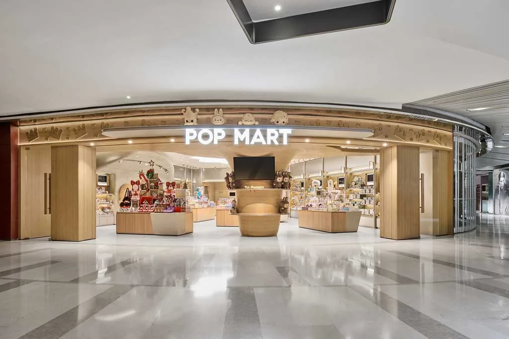 Ingresso del flagship store POP MART a Sanlitun con facciata in legno chiaro e display immersivo ispirato ai personaggi IP