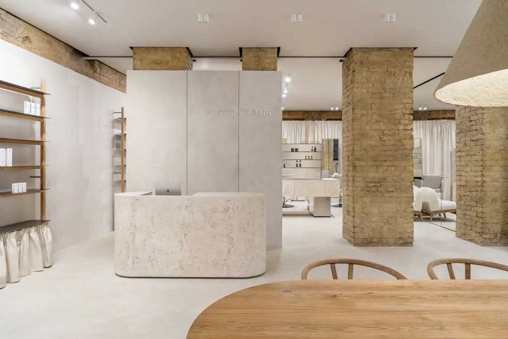 Travertine reception and exposed brick columns in the PLEKA Showroom in Kyiv