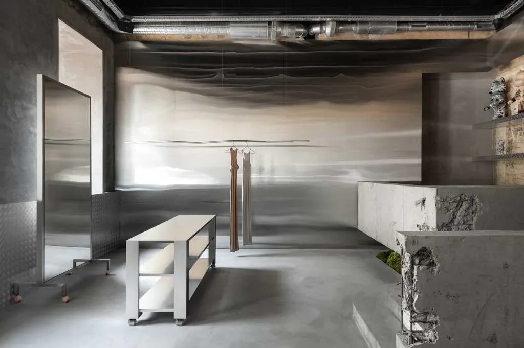 Spazio espositivo di Domaine 17 a Kiev con pareti in acciaio ondulato, arredi minimalisti e specchi mobili con ruote rosa.