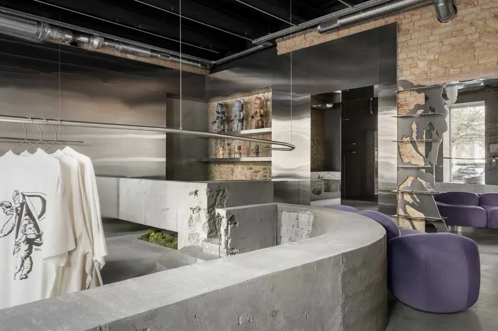 Interni di Storage x Domaine 17 a Kiev con pareti specchianti, cemento grezzo, arredi curvi e dettagli scultorei in metallo lucido.