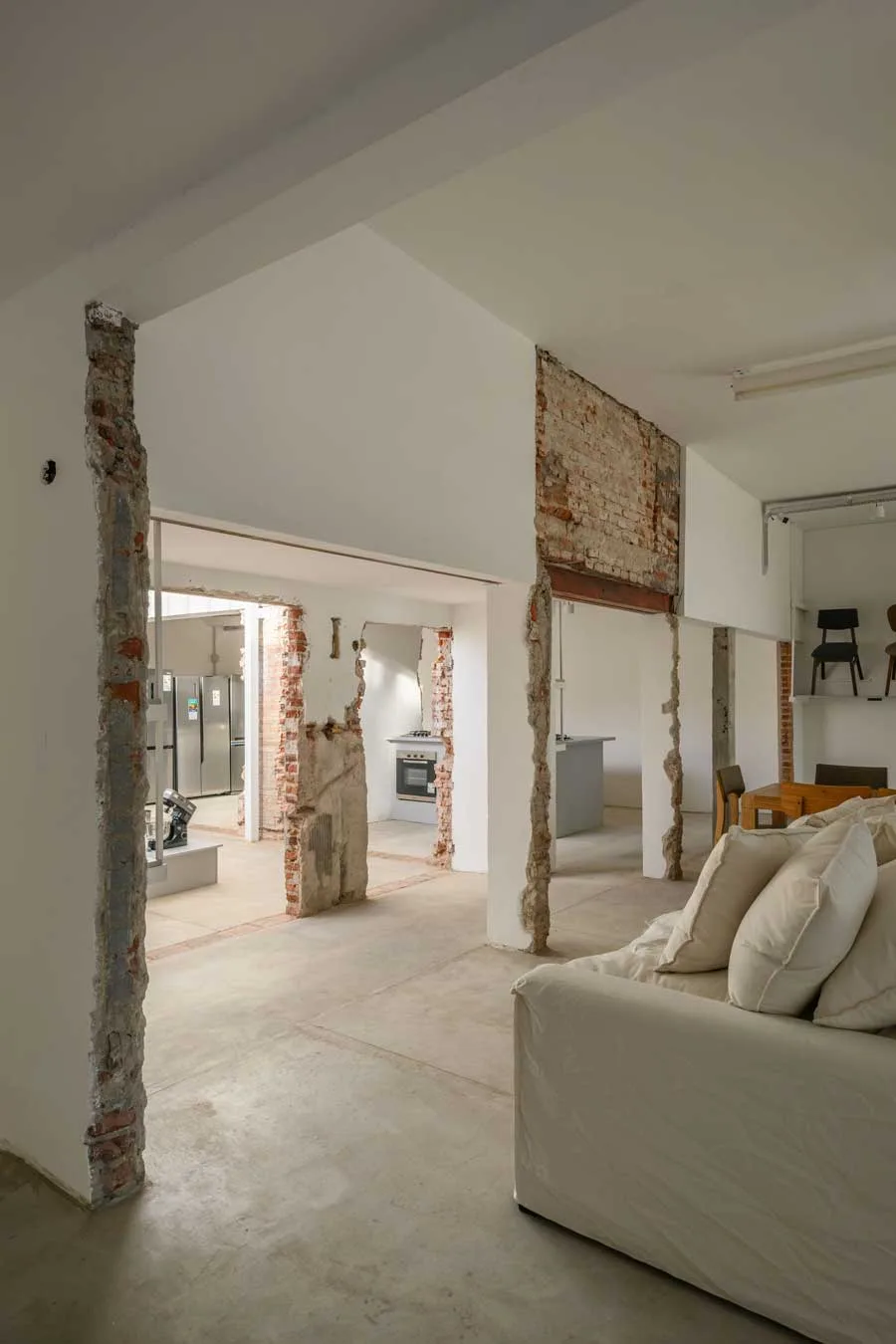Tracce murarie a vista e partizioni rimosse nel progetto di trasformazione architettonica di Natalia Hogar, tra zona living ed esposizione elettrodomestici