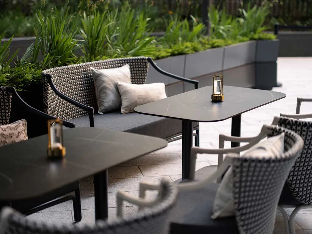 Outdoor area of Yung’s Bistro restaurant in Hong Kong with black and white rattan furniture and black stone tables.