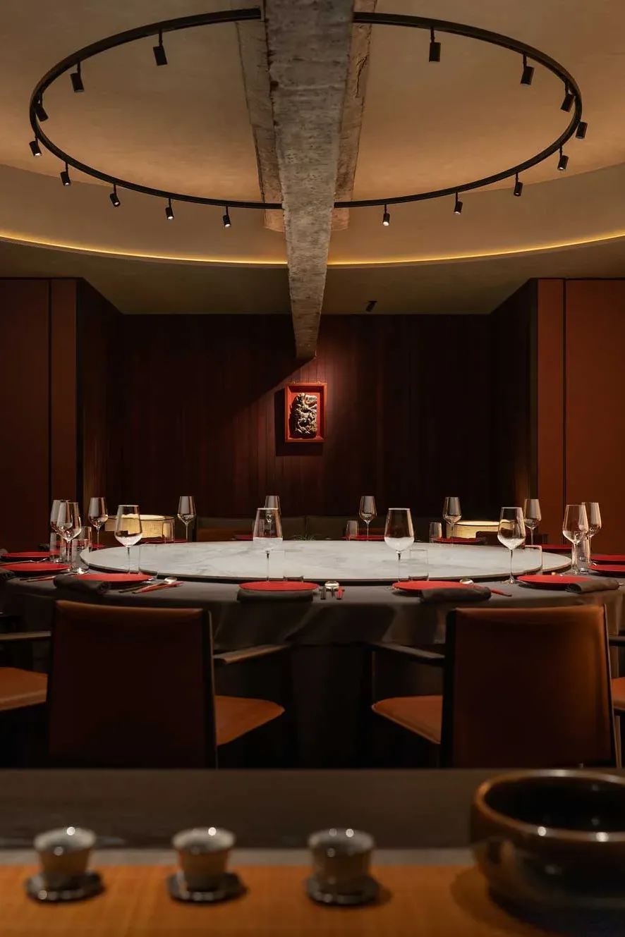 Dettaglio della sala privata del ristorante GUI TEMPLE a Pechino con tavolo rotondo in marmo e illuminazione scenografica
