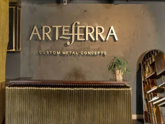 Reception dello showroom Arteferra a Delhi con bancone in metallo su misura e logo su parete in cemento