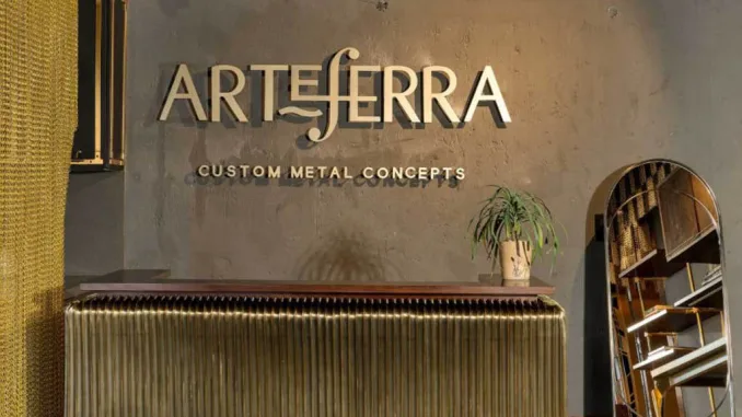 Reception dello showroom Arteferra a Delhi con bancone in metallo su misura e logo su parete in cemento