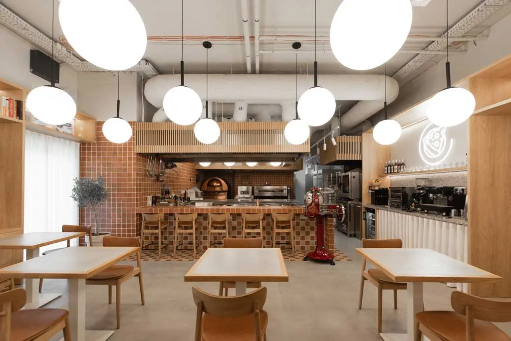 Vista della sala centrale con forno in rame e lampade sferiche – progettazione pizzerie contemporanee