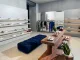 Interni della boutique Autry in Rue Saint-Honoré a Parigi con tavolo in travertino rosso e seduta blu, tra design materico e sneakers esposte