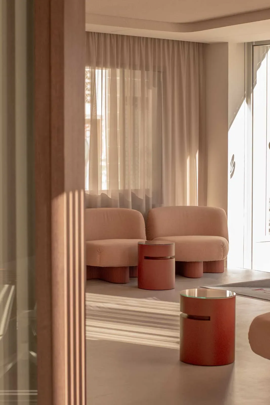 Dettaglio lounge con sedute rosa e tavolini cilindrici in uno studio dentistico accogliente