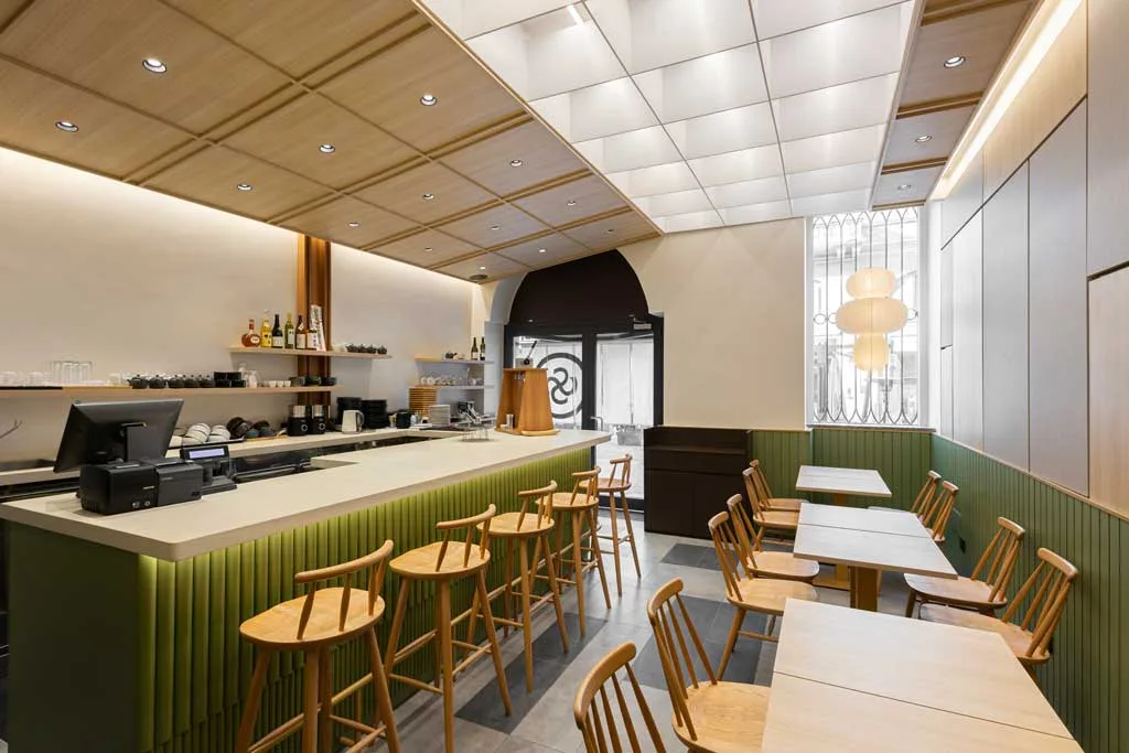 Interno del Kagurazaka Saryo Milano con bancone rivestito in verde matcha, arredi in legno naturale e soffitto geometrico ispirato al design giapponese