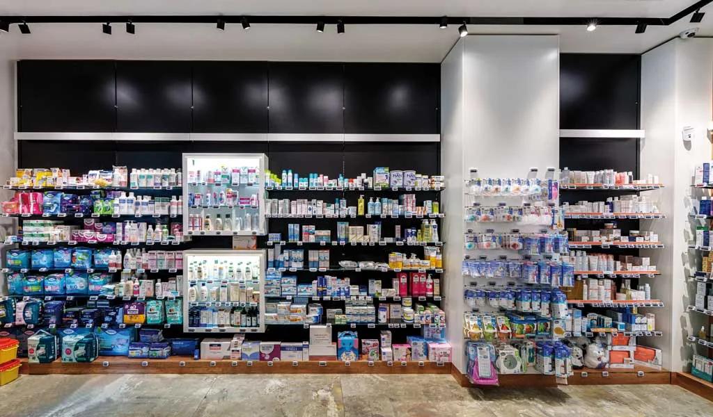 Parete espositiva retroilluminata con prodotti ordinati in farmacia moderna