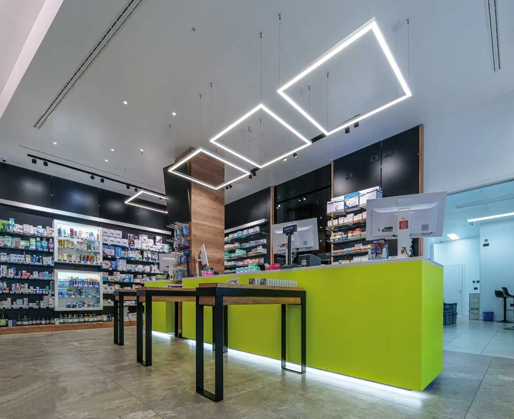 Bancone giallo fluo e sistemi di illuminazione a LED in farmacia su misura