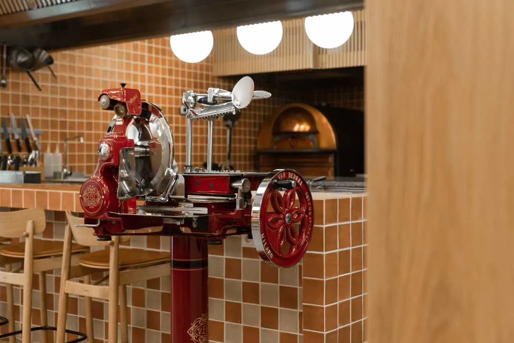 Affettatrice rossa e forno a legna con piastrelle mediterranee – dettagli iconici per Bidfood pizza academy