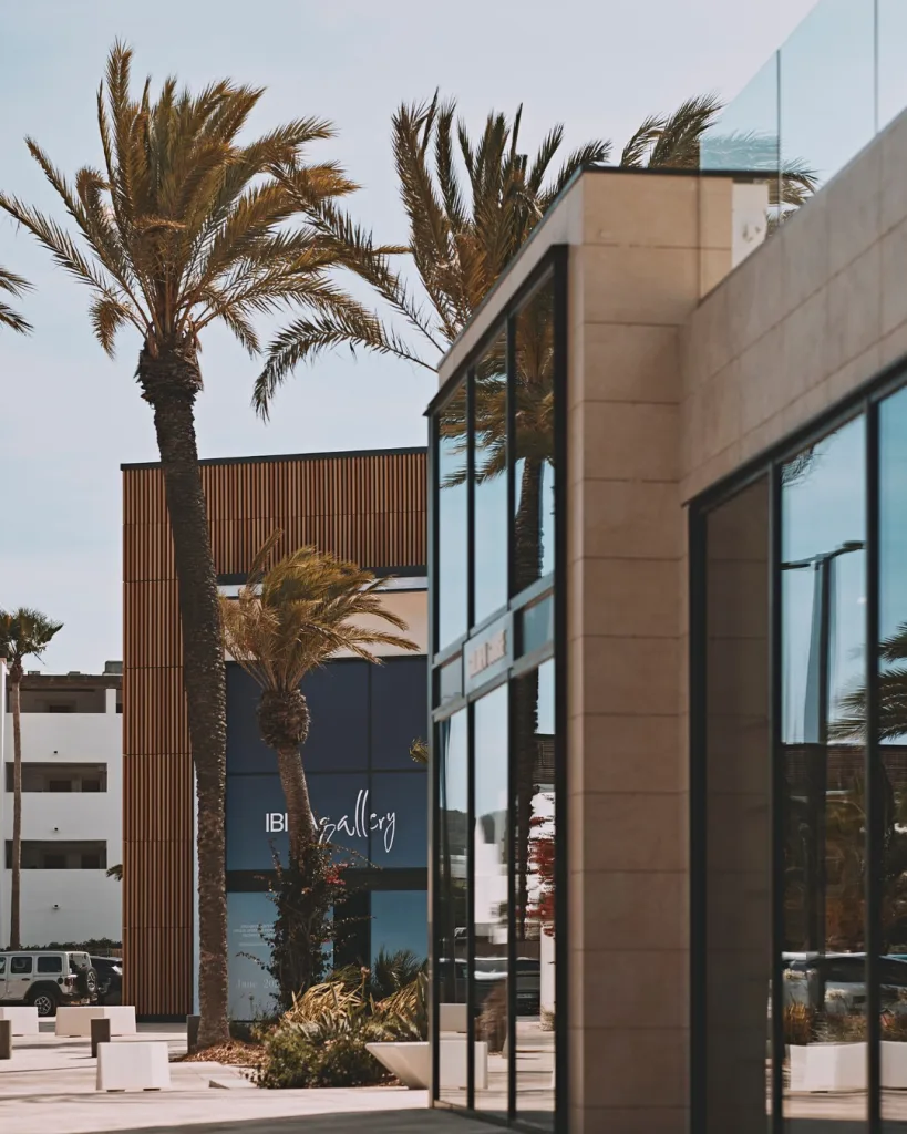 Dettaglio architettonico di IBIZA Gallery a Playa d’en Bossa – facciata in vetro, finiture naturali e palme mediterranee per un’estetica contemporanea.