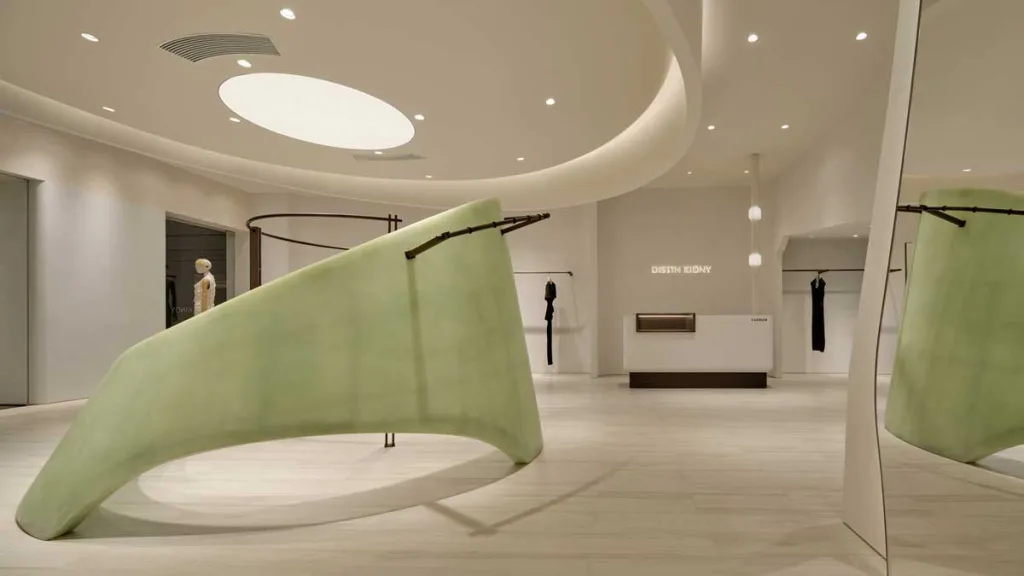 Interni del concept store DISTIN KIDNY a Chongqing con elementi curvilinei, palette neutra e desk minimale
