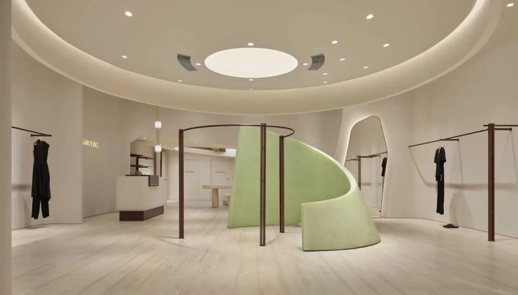 Vista interna del concept store DISTIN KIDNY a Chongqing con struttura curvilinea verde, illuminazione soffusa e arredi minimal