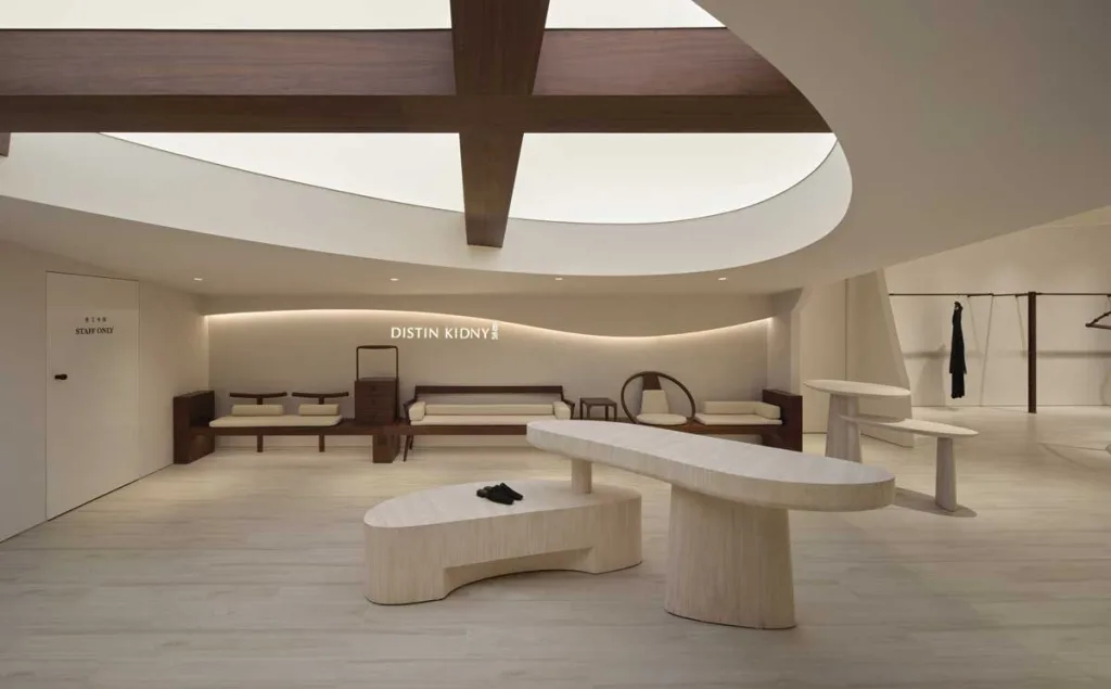 Area lounge del concept store DISTIN KIDNY a Chongqing con arredi organici in legno chiaro, luci soffuse e dettagli curvilinei