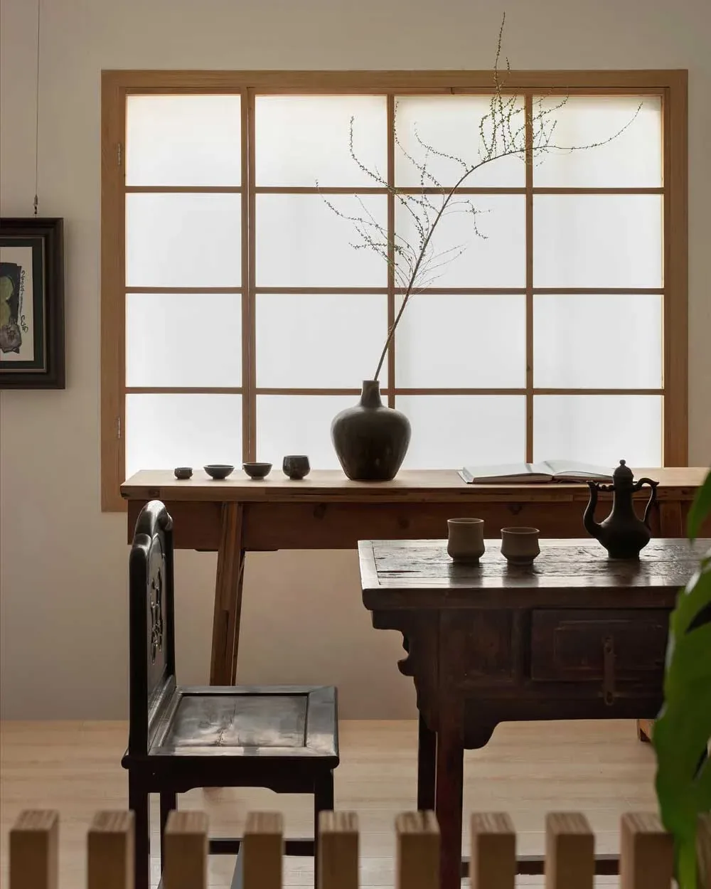 Dettaglio di un angolo contemplativo nella teahouse artistica a Foshan con tavolini in legno, sedia in stile tradizionale e luce filtrata da pannelli in carta