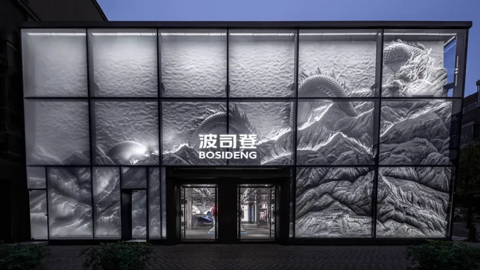 Facciata vetrata del flagship store Bosideng a Sanlitun con motivi metallici minimali Installazione scultorea ispirata all’Everest all’interno dello store Bosideng Dettaglio del drago in giada nello store Bosideng di Pechino Ambiente immersivo al secondo piano del flagship store Bosideng a Sanlitun Passerella interattiva ispirata all’Antartide nel negozio Bosideng a Pechino