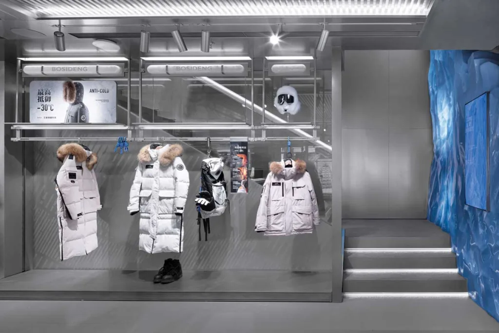 Display of cold-resistant technical garments inside the Bosideng flagship store in Sanlitun – layout detail with metallic walls and icy textures.