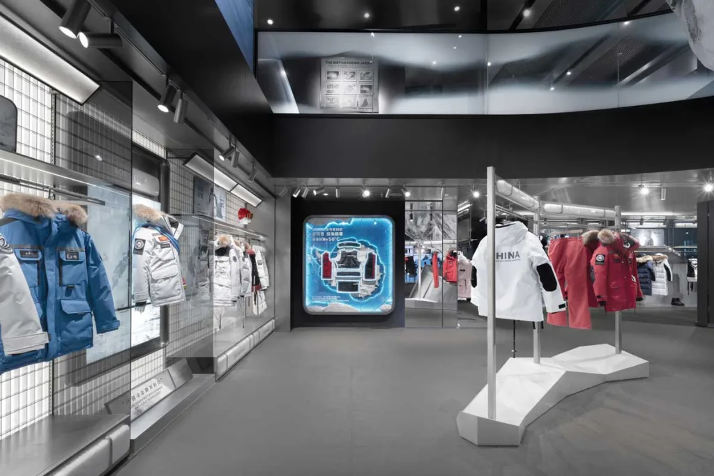 View of the Bosideng winter collection featuring expedition garments and a backlit interactive panel – interior design of the flagship store in Sanlitun.