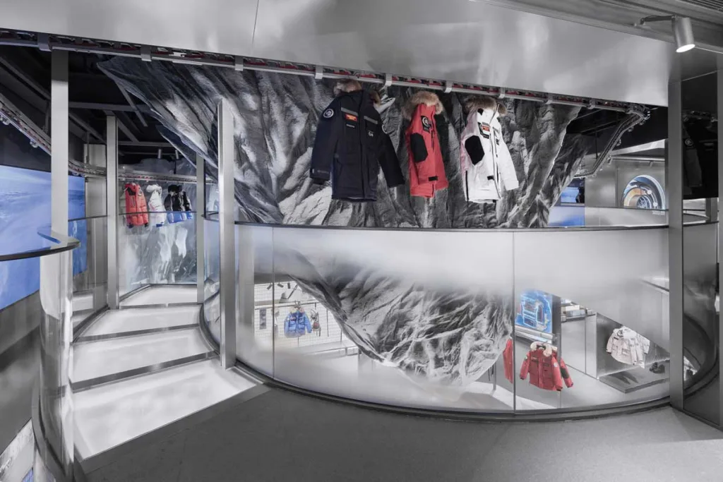 Elevated display walkway featuring technical coats and a sculptural relief wall – interior design of the Bosideng flagship store in Sanlitun.