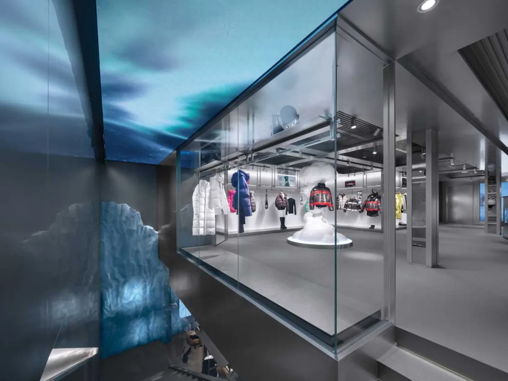 View of the exhibition hall from the upper floor featuring a central installation and backlit displays – immersive experience of the Bosideng flagship store.