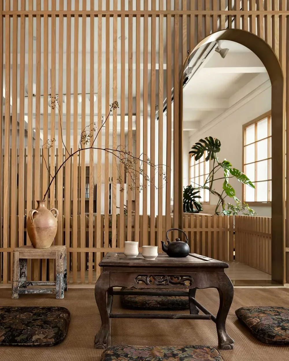 Area cerimoniale nella teahouse artistica a Foshan con tavolino in legno intagliato, cuscini a terra e ambientazione tradizionale ispirata al rito del tè