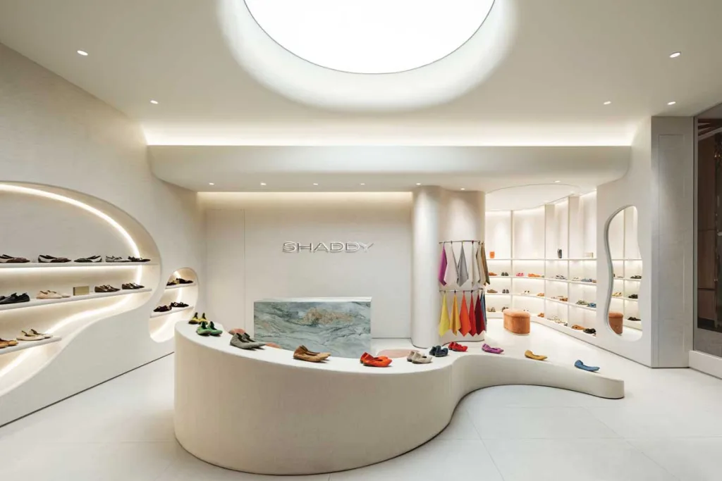 Interni del Shaddy Store a West Jakarta con espositori curvi retroilluminati, banco in marmo e palette neutra