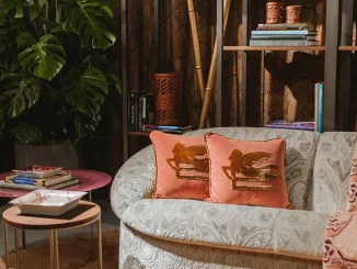 Angolo relax con divanetto curvo, cuscini decorativi e tappeto rosa all’interno dello showroom Etro a Ginza.