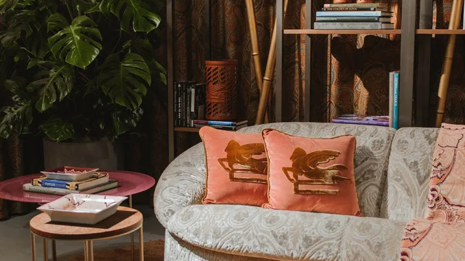 Angolo relax con divanetto curvo, cuscini decorativi e tappeto rosa all’interno dello showroom Etro a Ginza.