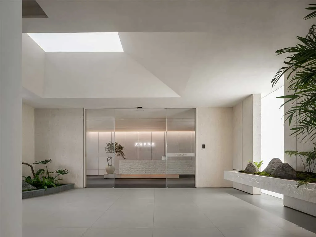 Ingresso dello showroom moda a Foshan progettato da LubanEra Design – luce zenitale, paesaggio vegetale e reception in pietra