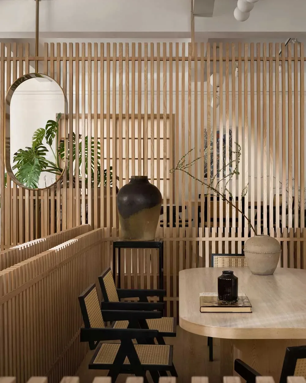 Zona conviviale della teahouse artistica a Foshan con arredi in legno, sedute in paglia di Vienna e vasi decorativi, separata da pareti in listelli verticali
