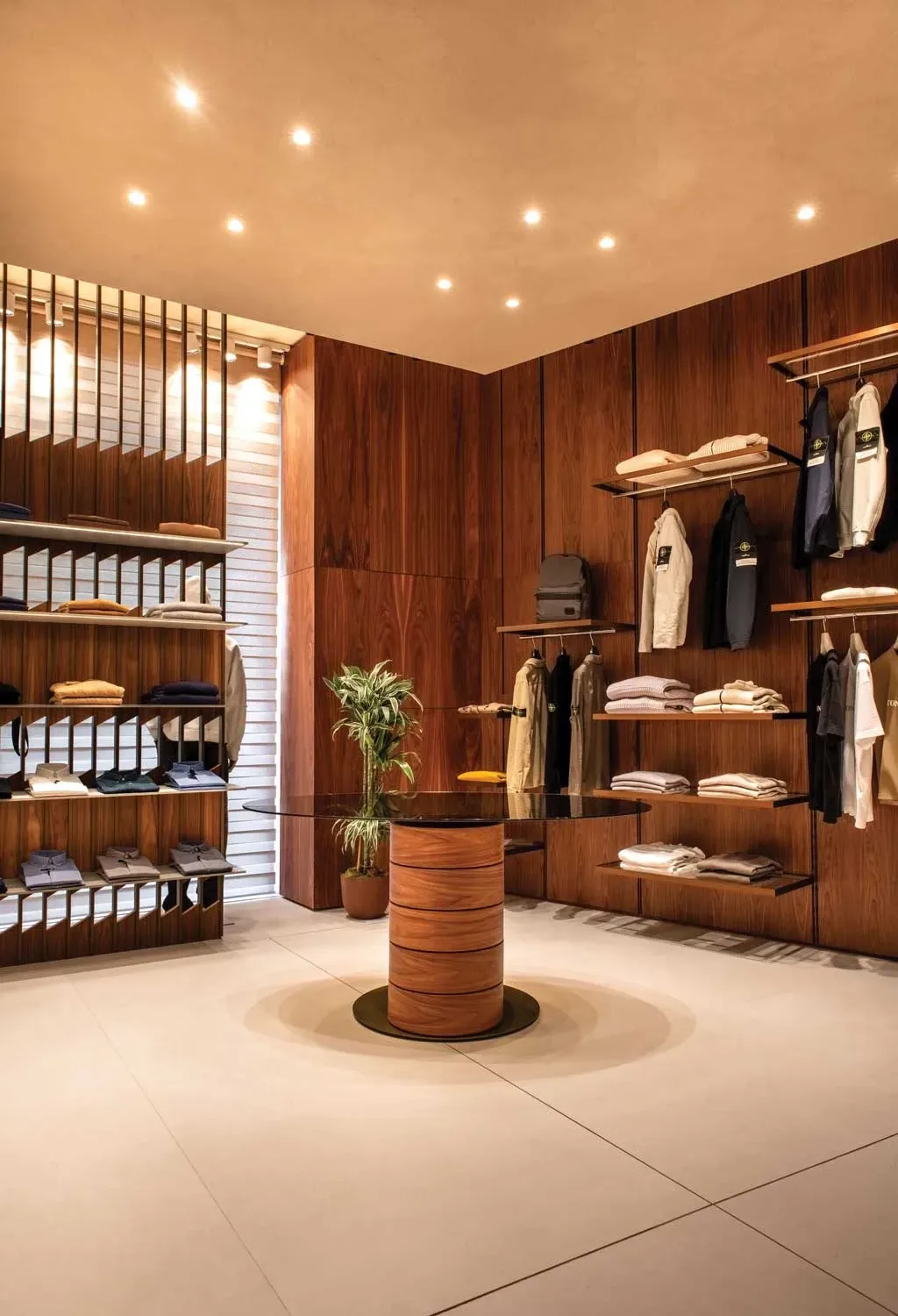 Interno della boutique Caposerio Uomo a Cefalù con arredi in legno di noce americano, espositori su misura e tavolo centrale con piano in vetro