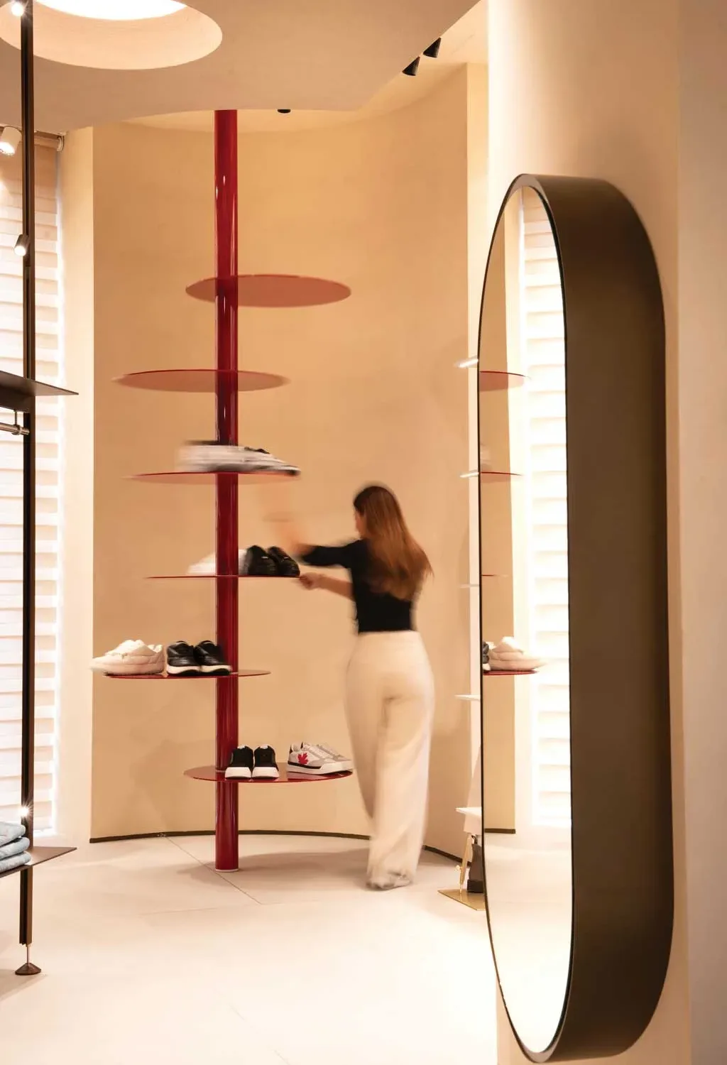 Espositore girevole rosso per calzature nella boutique Caposerio Uomo a Cefalù, progetto di Francesco Pitruzzella, con dettagli materici e luce naturale.