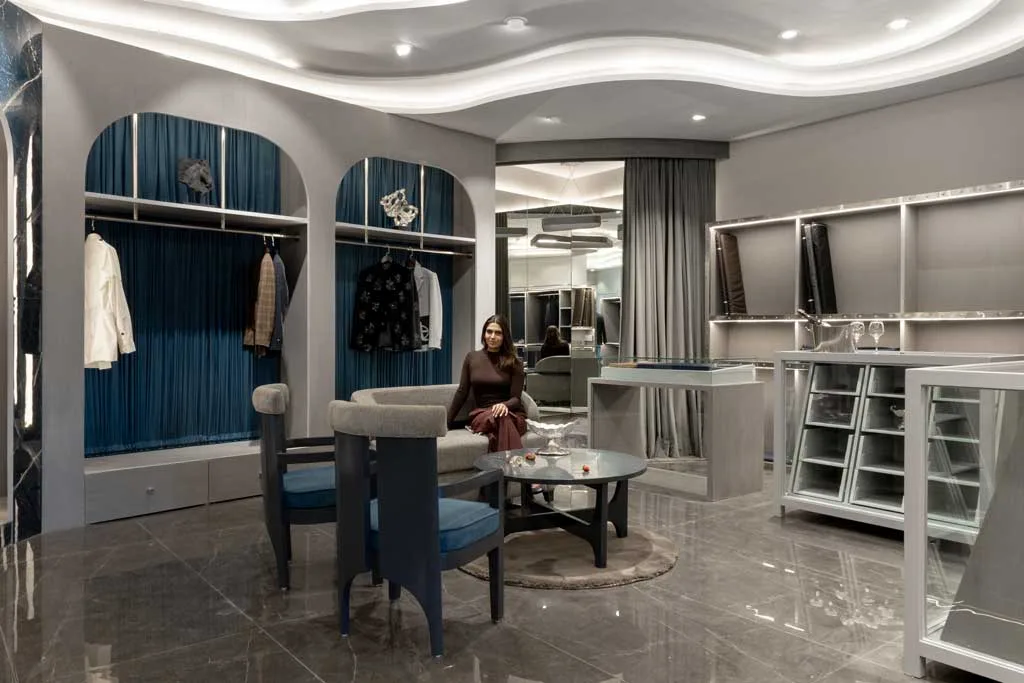 Central lounge of the Mukund Taneja Boutique in Amritsar with velvet seating, tailored displays, and backlit wavy ceiling.