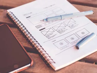 Quaderno con penne e smartphone, simbolo dell’evoluzione del design dal disegno manuale al digitale