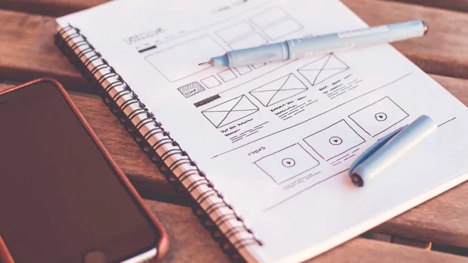 Quaderno con penne e smartphone, simbolo dell’evoluzione del design dal disegno manuale al digitale