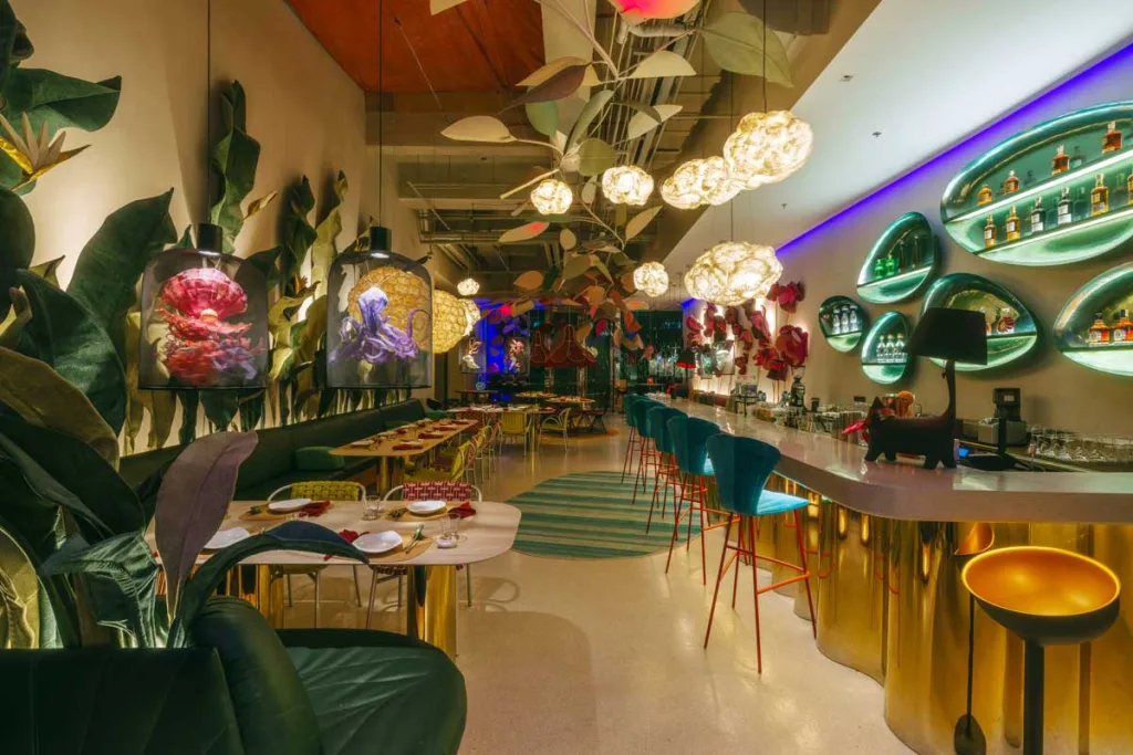 Vista degli interni immersivi del FABLE Café + Lounge a Manila con sedute colorate, luci floreali sospese e pareti artistiche ispirate alla natura