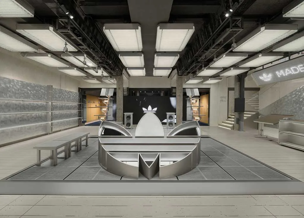 Interni del flagship store Adidas Originals a Shanghai con installazione centrale a forma di Trefoil e design industriale firmato TOMO Design